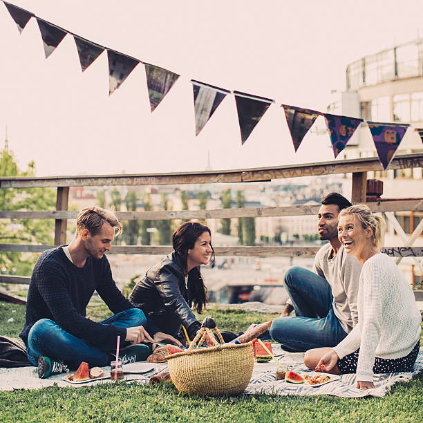 happy friends enjoying picnic on roof garden - garden decoration stock pictures, royalty-free photos & images