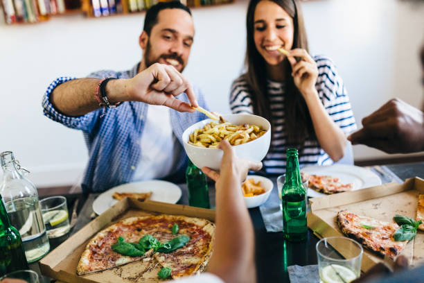 happy friends having french fries and pizza at home - junk food stock pictures, royalty-free photos & images
