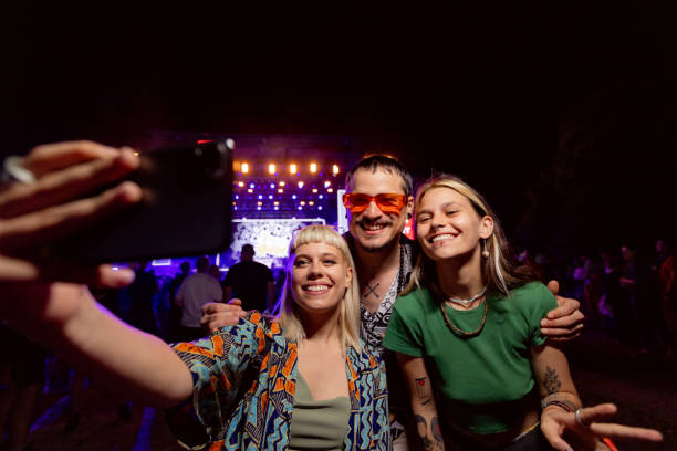 happy friends taking a selfie during a music concert by night. - concert stock pictures, royalty-free photos & images