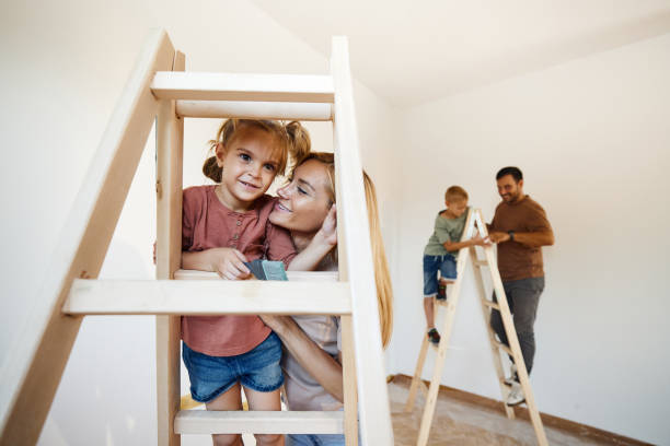 happy girl enjoying with her mother on ladders during home renovation process. - home decoration stock pictures, royalty-free photos & images