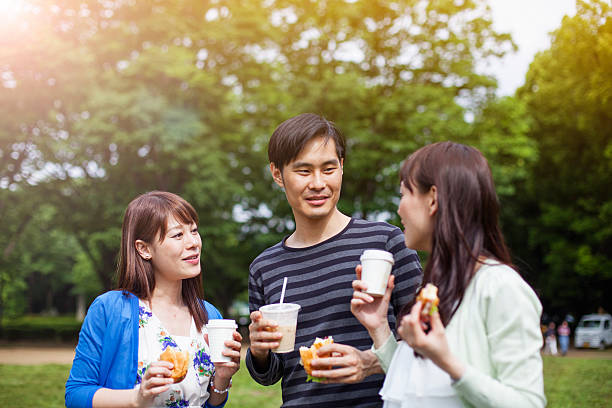 happy group of japanese friends eat in the park, tokyo - junk food stock pictures, royalty-free photos & images