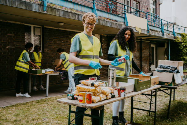 happy male volunteer giving canned food to female friend working in garden - food stock pictures, royalty-free photos & images