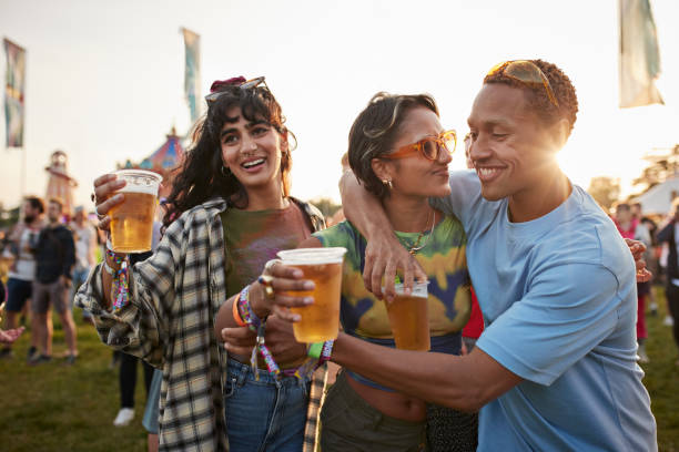 happy man with arm around girlfriend near friend - concert stock pictures, royalty-free photos & images