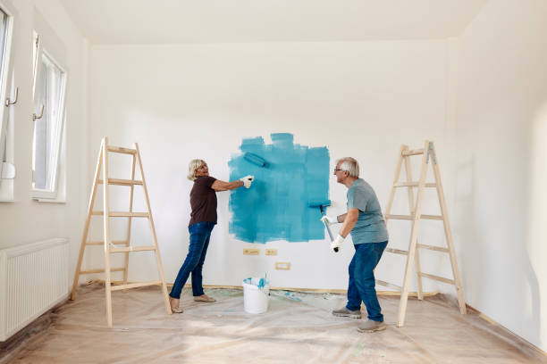 happy mature couple talking while painting their new apartment. - home decoration stock pictures, royalty-free photos & images
