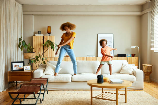 happy mother and son dancing on sofa at home - home decoration stock pictures, royalty-free photos & images