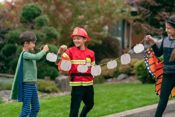 happy siblings celebrating halloween in their front yard - garden decoration stock pictures, royalty-free photos & images