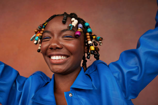 happy teenage girl with beads on braids against brown background - fashion stock pictures, royalty-free photos & images