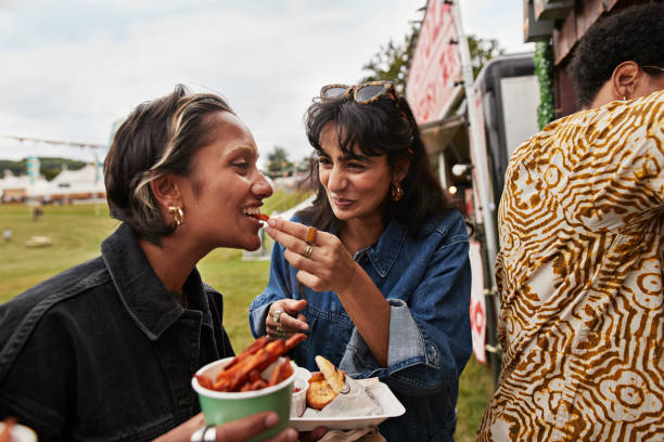 happy woman feeding female friend - food stock pictures, royalty-free photos & images