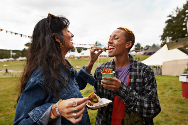 happy woman feeding street food to boyfriend - concert stock pictures, royalty-free photos & images