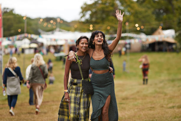 happy woman with female friend waving while walking - concert stock pictures, royalty-free photos & images