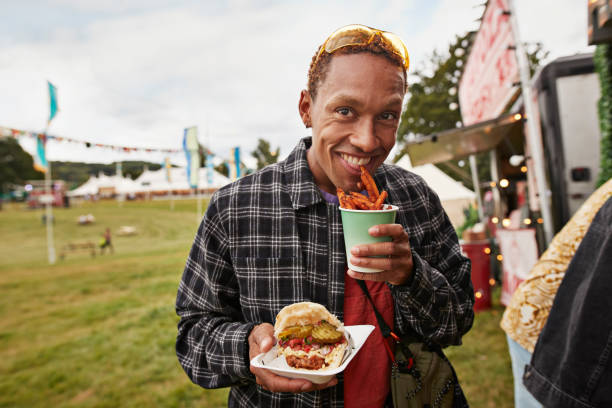 happy young man eating take out street food - concert stock pictures, royalty-free photos & images