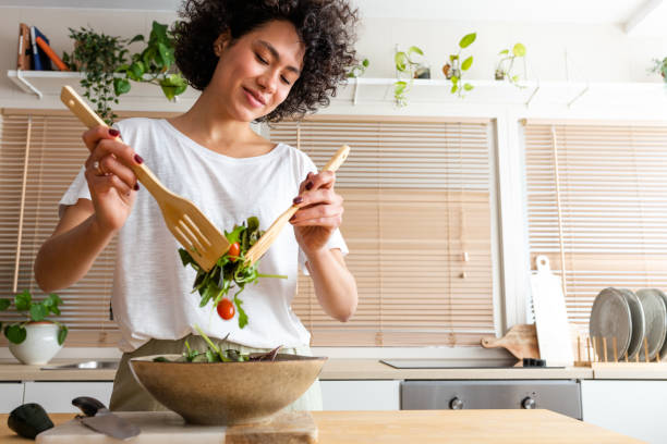 happy young multiracial woman mixing bowl of fresh salad. copy space.healthy lifestyle - food stock pictures, royalty-free photos & images