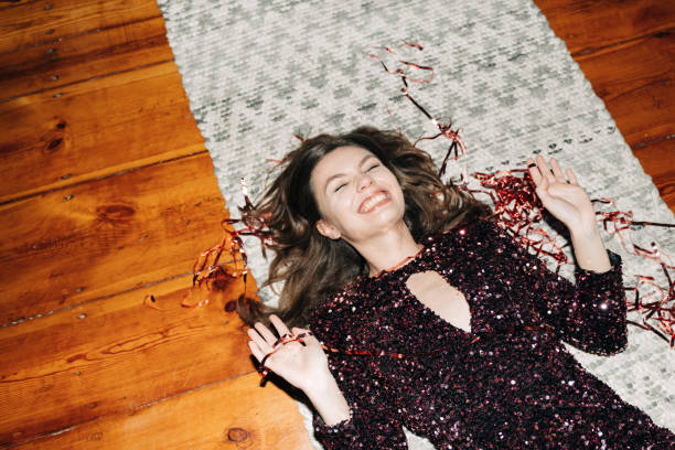 happy young woman in glittering cocktail dress on carpet floor, flash light, user generated content - fashion stock pictures, royalty-free photos & images