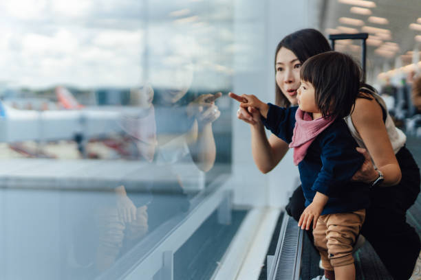 headshot of mother and toddler looking at view at the airport - travel stock pictures, royalty-free photos & images