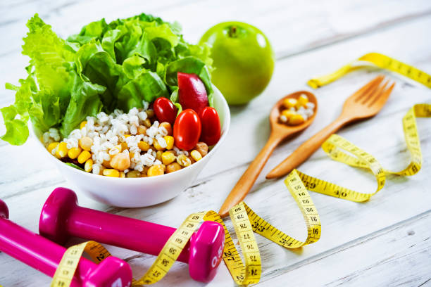 healthy eating and exercising backgrounds: fresh healthy salad, dumbbells and tape measure with copy space - junk food stock pictures, royalty-free photos & images