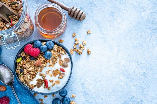 healthy food: homemade yogurt and granola shot from above on blue table. copy space - food stock pictures, royalty-free photos & images