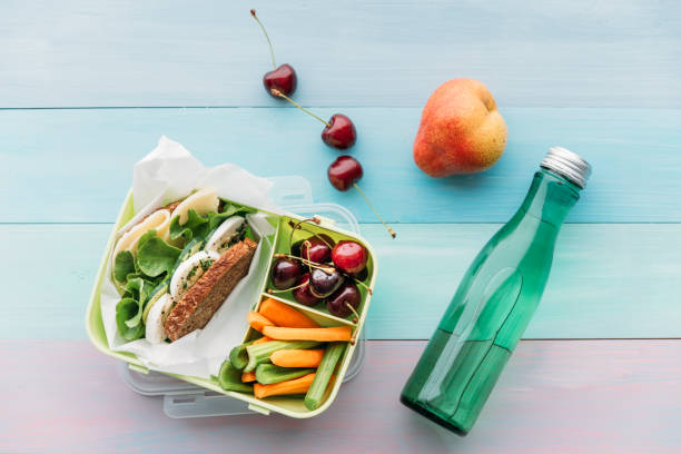healthy school food in a lunch box, vegetarian sandwich with cheese, lettuce, cucumber, egg and cress, sliced carrot and celery, cherries and pear - junk food stock pictures, royalty-free photos & images