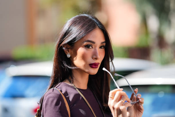 Heart Evangelista wears clear sunglasses, dark brown red burgundy long sleeve Fendi maxi dress, outside Fendi, during the Milan Fashion Week...