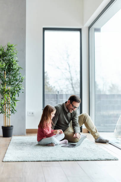 heureux père célibataire et sa fille utilisant un ordinateur à la maison. - home decoration photos et images de collection