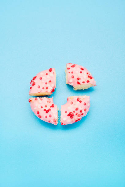 high angle view of a donut divided into four parts on blue background, symbol for pie chart - junk food stock pictures, royalty-free photos & images