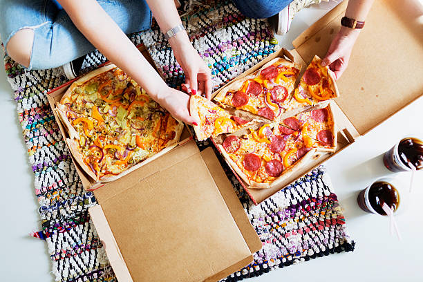 high angle view of friends eating pizza with cola in new home - junk food stock pictures, royalty-free photos & images