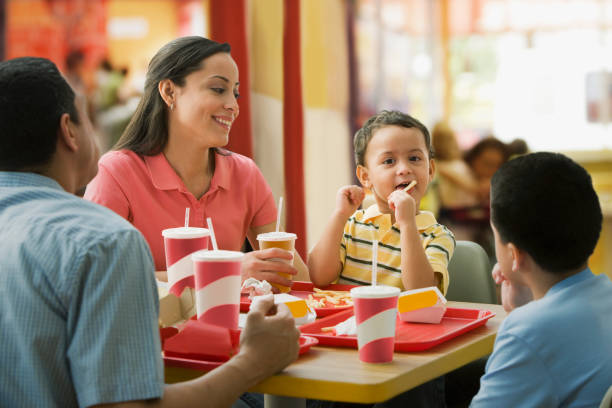 hispanic family eating in fast food restaurant - junk food stock pictures, royalty-free photos & images