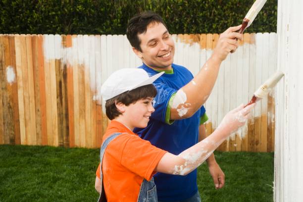 hispanic father and son painting fence - garden decoration stock pictures, royalty-free photos & images