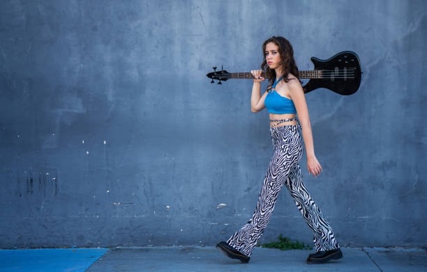 hispanic girl walking with electric guitar on a sidewalk - fashion stock pictures, royalty-free photos & images