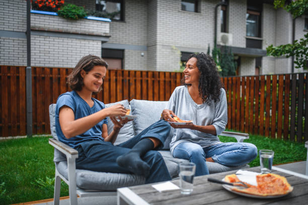hispanic mother and son eating pizza outdoors - junk food stock pictures, royalty-free photos & images