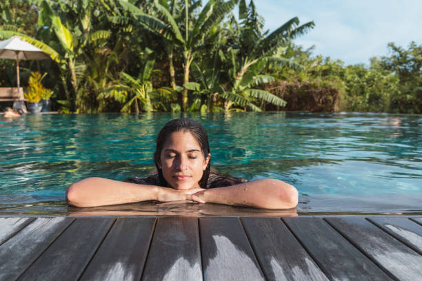 hispanic woman at hotel tropical resort sunbathing with palm trees in background - travel stock pictures, royalty-free photos & images