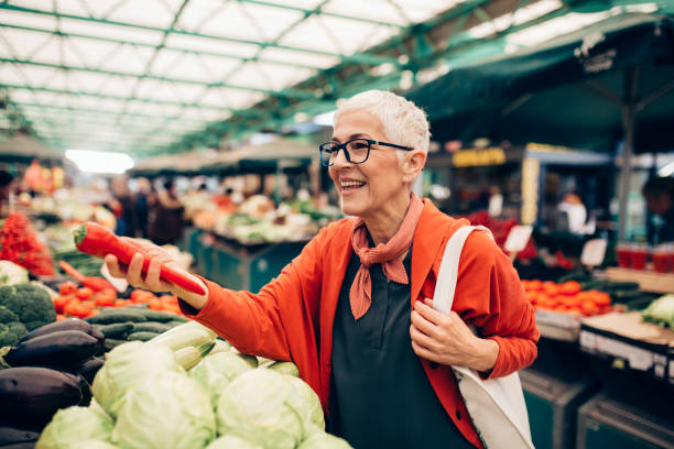 hogere vrouw die bij de markt van de landbouwer winkelt - food stockfoto's en -beelden