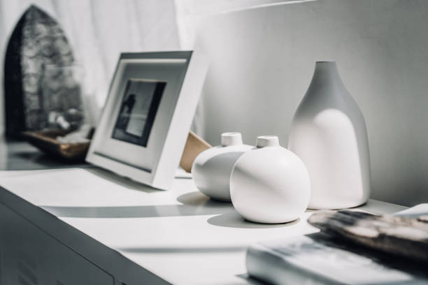 home decoration of neutral coloured vases and picture frame on a cabinet by the window in sunlight - home decoration stock pictures, royalty-free photos & images