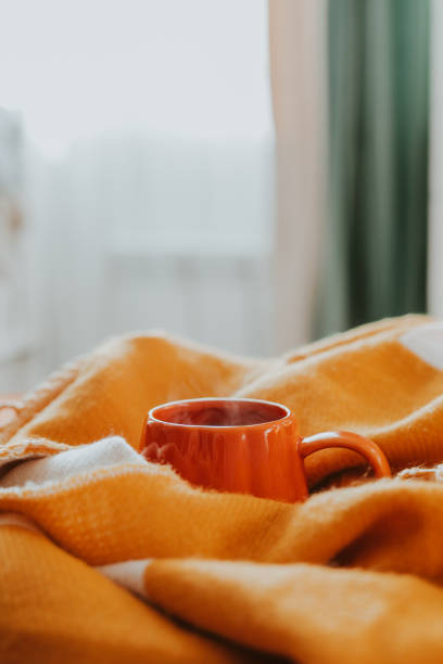 hot tea with steam in orange cup on bed in bedroom. copy space. cozy autumn or winter concept. - home decoration stock pictures, royalty-free photos & images