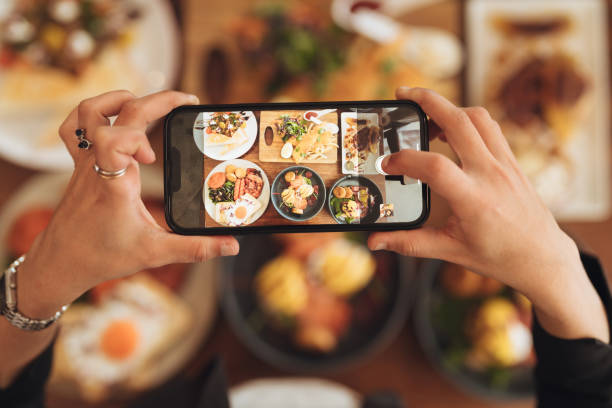 human hand holding phone taking photo of food. - food stock pictures, royalty-free photos & images