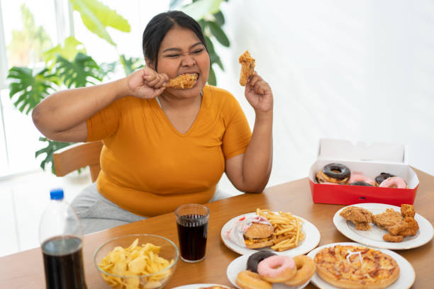 hungry overweight woman holding fried chicken - junk food stock pictures, royalty-free photos & images