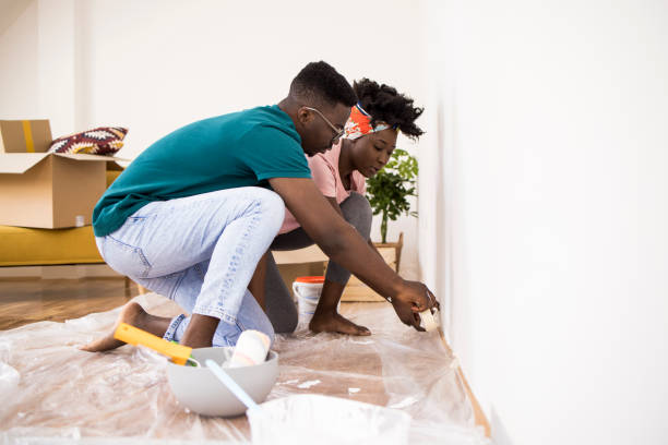 husband helping wife while painting apartment together - home decoration stock pictures, royalty-free photos & images