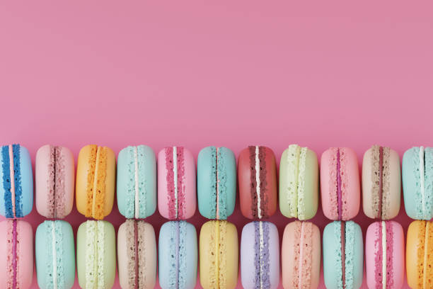illustration 3d of a group of different colored macaroons lined up on a pink background. - junk food stock-fotos und bilder