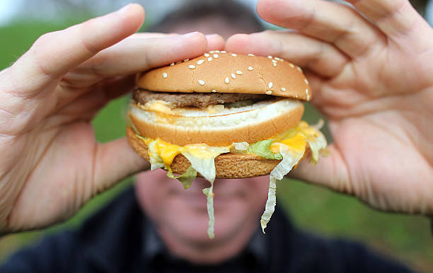 In this photo-illustration a man holds a burger from a fast food outlet on January 7, 2013 in Bristol, England. A government-backed TV advert - made...