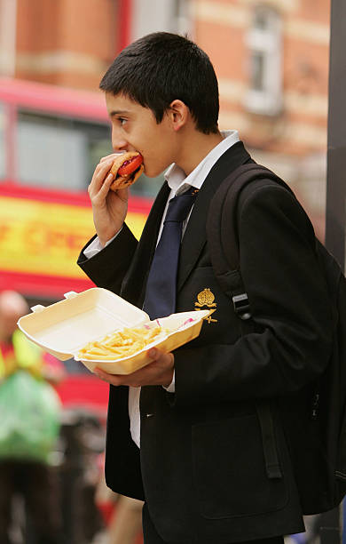 In this photo illustration school student Amir Shahin eats a burger and chips as part of his lunch which was brought from a fast food shop near his...