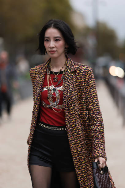 Irene Kim is seen outside Chanel show wearing gold Chanel necklaces, yellowish tweed Chanel coat, black leather shorts, golden Chanel belt, black...