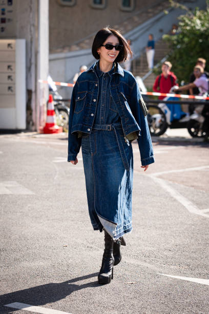 Irene Kim wears a blue denim shirt, blue denim jacket, denim midi skirt and black boots, outside Sacai, during the Womenswear Spring/Summer 2024 as...