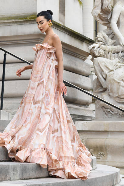 Izabelle Angus wears white and silverleather heeled sandals, a pink floral printed ruffles long maxi dress and gold earrings outside Zimmermann...