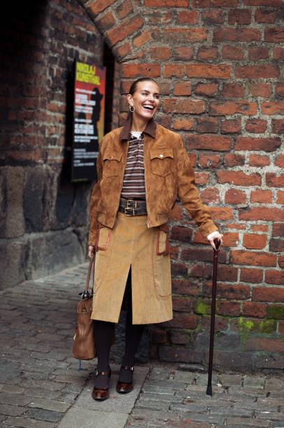 Janka Polliani wears brown cowboy shoes, brown skirt, brown suede jacket, brown striped polo shirt and a brown leather bag with bag charms or...