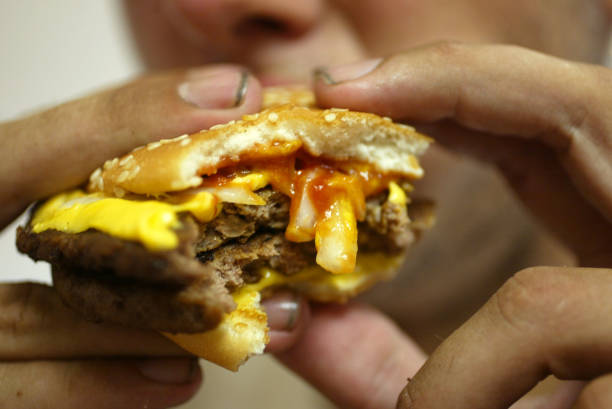 Jeff Baughman bites into his Double Quarterpounder with cheese on July 18, 2002 at a McDonalds in Miami Beach, Florida. The health effects of an...