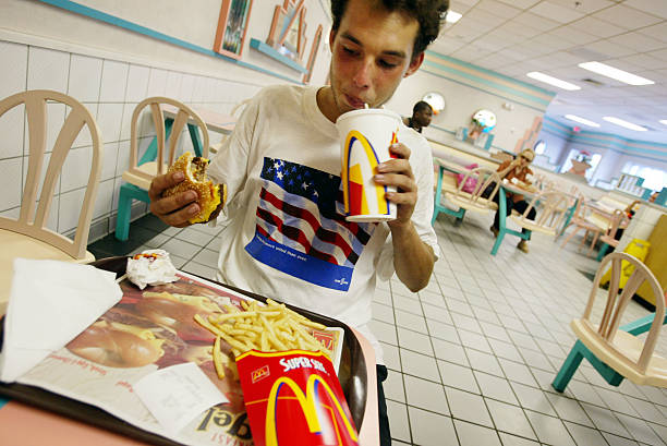 Jeff Baughman takes a sip of his Super Coke as he eats his Double Quarterpounder with cheese along with a Super Fry on July 18, 2002 at a McDonalds...