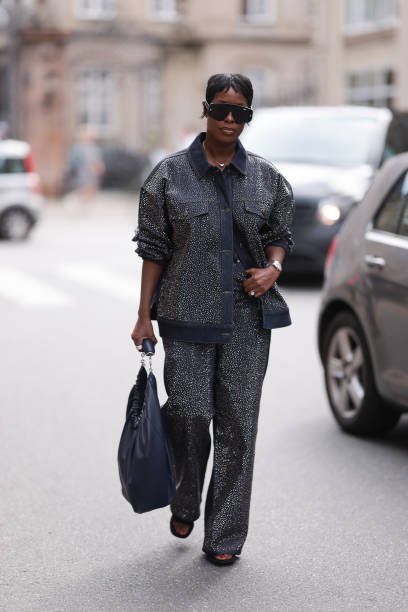 Jenee Naylor is seen wearing large black sunglasses from Dior, a necklace with silver heart pendant, a dark denim jacket covered with rhinestones,...