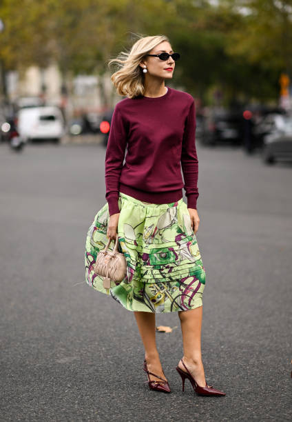 Jenny Walton is seen wearing a maroon sweater, green floral skirt, Miu Miu bag and black sunglasses with pearl earrings outside the Miu Miu show...