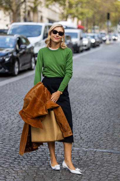 Jenny Walton wears green jumper, high waisted black skirt, white pointed heels outside Carven during the Womenswear Spring/Summer 2024 as part of...