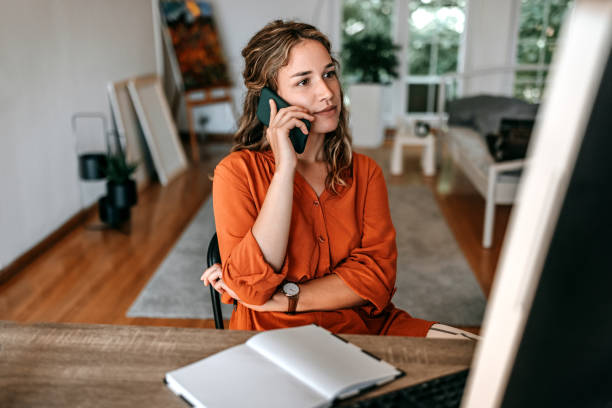 jeune femme parlant sur un téléphone intelligent au bureau à domicile - home decoration photos et images de collection