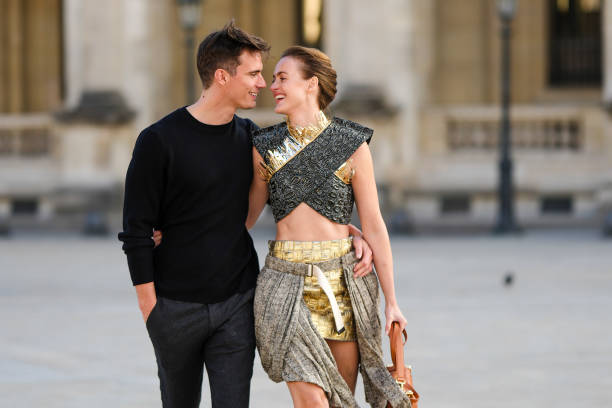 Jonathan Nielssen wears a black wool pullover, dark gray suit pants, Renate Reinsve wears a gray with black leopard embossed pattern and gold fringed...
